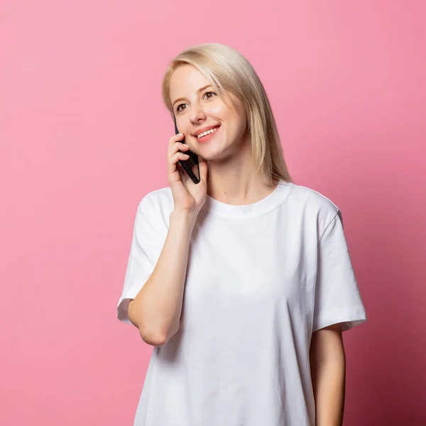 Blondynka Białej Bluzce Moch Telefonem Komórkowym Różowym Tle — Zdjęcie stockowe
