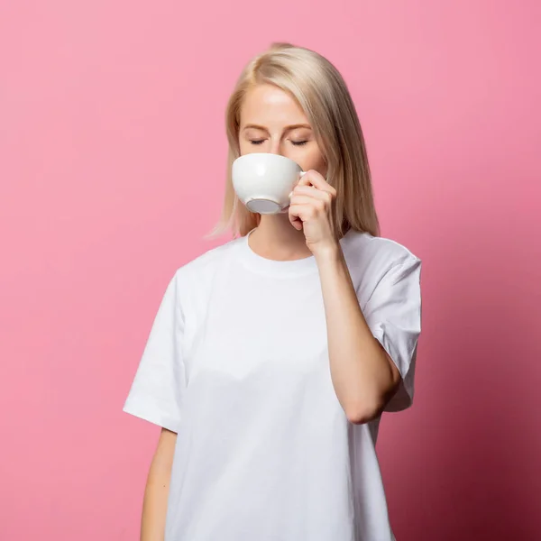 Blond Kvinna Vit Moch Shirt Med Kopp Kaffe Rosa Bakgrund — Stockfoto