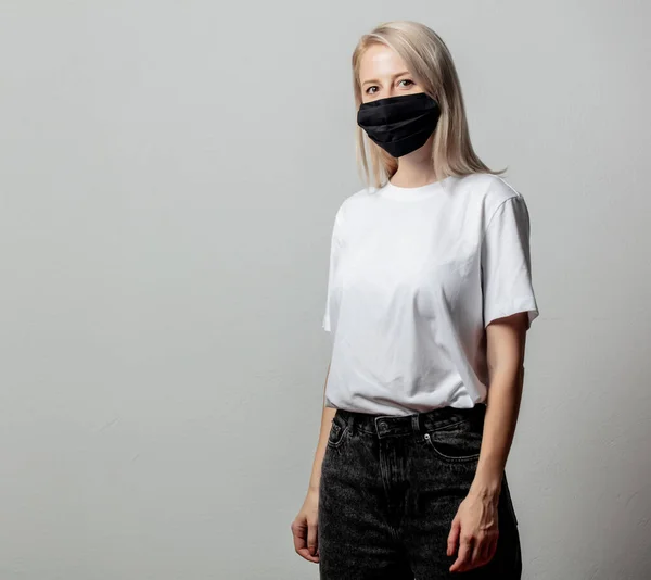 Woman in white t-shirt and black face mask on white background