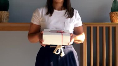 Kadın kafede içinde kek olan bir kutu tutuyor.