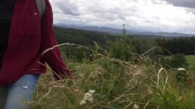 Kız dağların arka planında çayırda yürüyor.