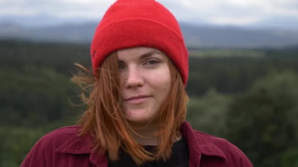 Gadis Muda Bertopi Merah Tanpa Make Melihat Kamera Dengan Gunung — Stok Video