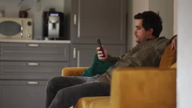 Kanepede oturan şişman adam cep telefonuyla.