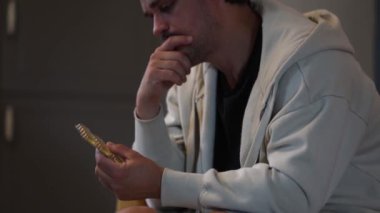 Bacalı adam kanepede haplarla oturuyor.