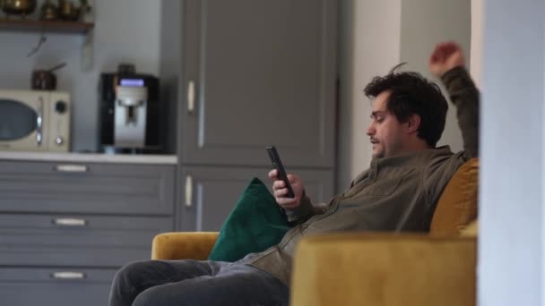 Dicker Mann Sitzt Mit Handy Auf Der Couch — Stockvideo
