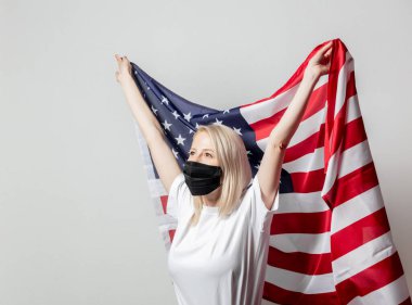 Beyaz arka planda Amerikan bayrağı olan maskeli sarışın kız. 