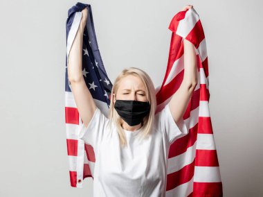 Beyaz arka planda Amerikan bayrağı olan maskeli sarışın kız. 