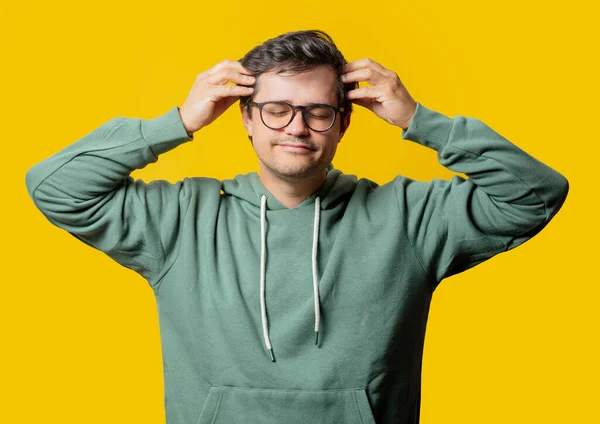 Man Met Hoofdpijn Groene Hoodie Gele Achtergrond — Stockfoto