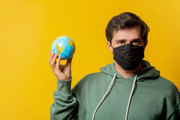 Yüz Maskeli Adam Sarı Arka Planda Dünya Tutuyor — Stok fotoğraf