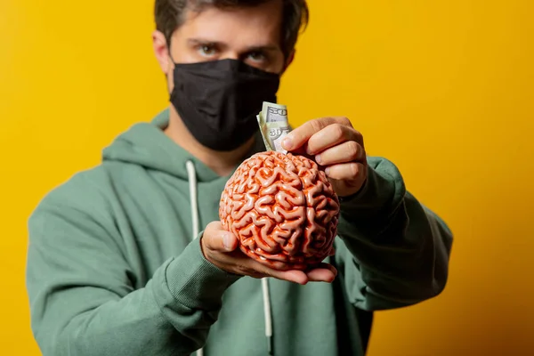 Tipo Mascarilla Mantener Cerebro Humano Con Dinero Sobre Fondo Amarillo —  Fotos de Stock