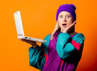 Turuncu arka planda not defteri olan 90 'ların eşofmanlı stil kadını.