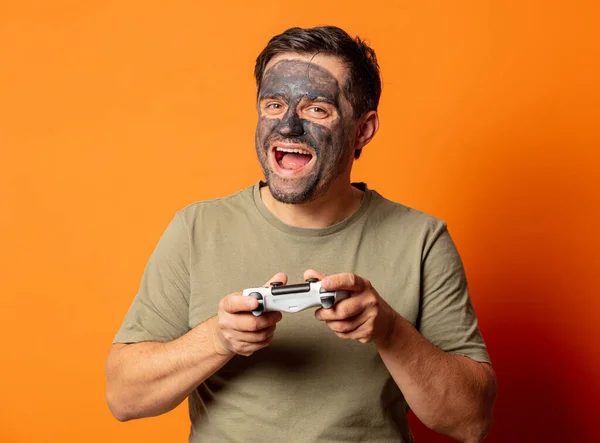 Huy Sorridente Com Máscara Cosmética Controlador Jogo Fundo Laranja — Fotografia de Stock