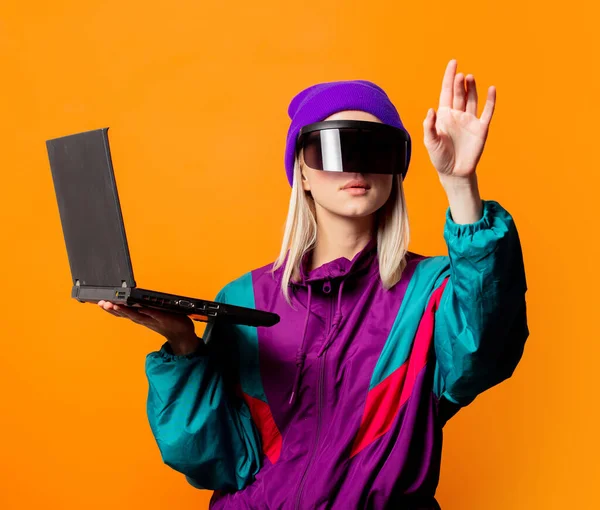 90年代风格女人的运动服和Vr眼镜 背景是橙色的笔记本电脑 — 图库照片