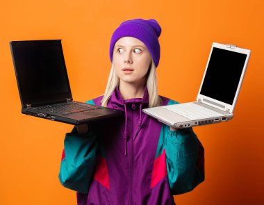 90 'ların eşofmanlı, turuncu arka planda iki defter olan stil kadını.