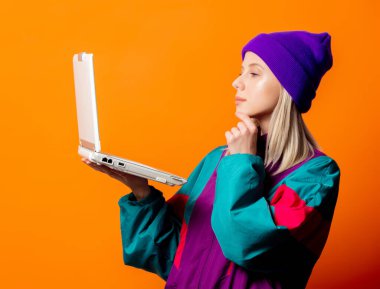 Turuncu arka planda not defteri olan 90 'ların eşofmanlı stil kadını.