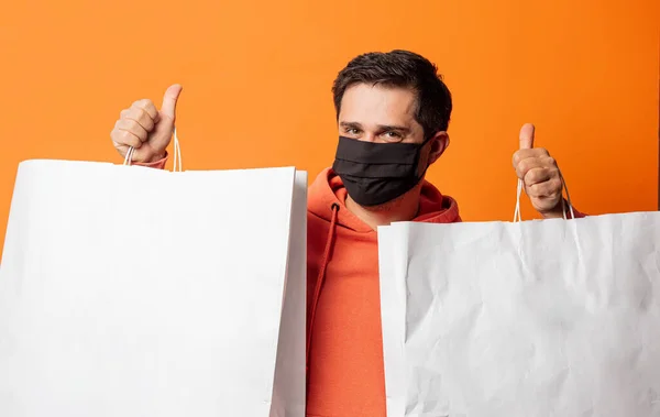 Cara Máscara Facial Com Sacos Compras Fundo Laranja — Fotografia de Stock