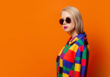 90 'ların kıyafetleri ve turuncu arka planda güneş gözlüklü stil kızı. 