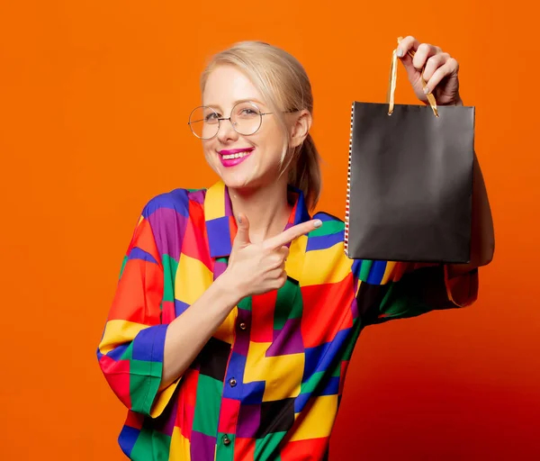 90年代风格金发女郎穿着黑色购物袋橙色背景的衣服 — 图库照片