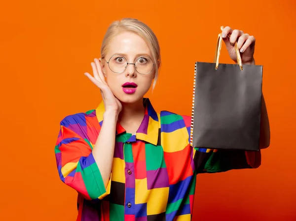 スタイルブロンドで90年代服とともに黒ショッピングバッグ上のオレンジ背景 — ストック写真