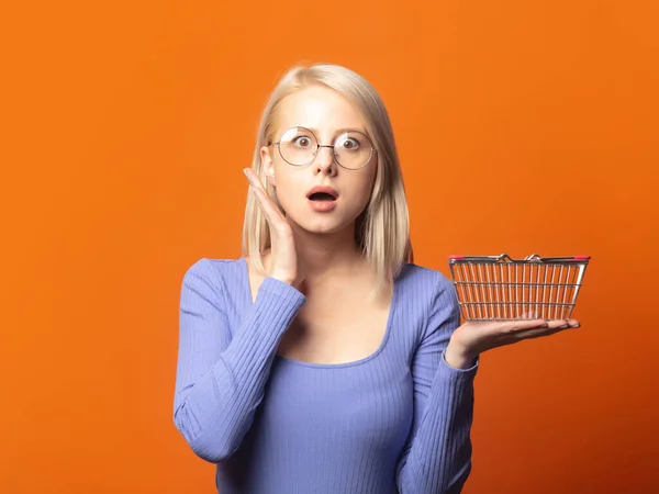Nette Blondine Blauer Bluse Mit Einkaufskorb Auf Üppigem Orangefarbenem Hintergrund — Stockfoto