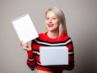 Gri arka planda beyaz hediye kutusuyla gülümseyen kız. 