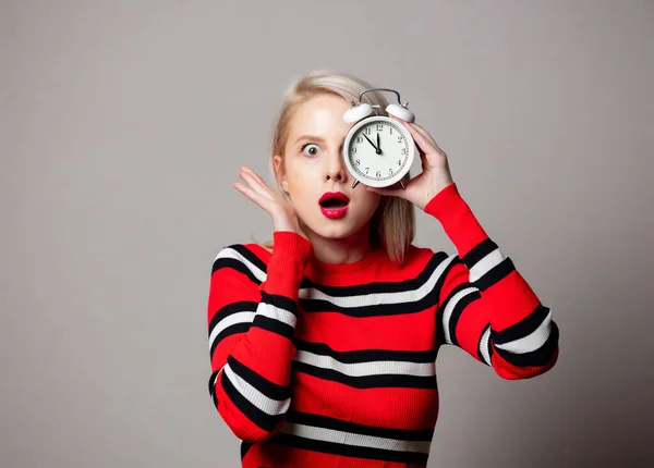 スタイル女の子で赤いセーターとともに目覚まし時計上の灰色の背景 — ストック写真