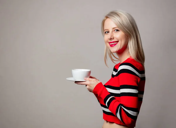 Stilvolle Blondine Roten Pullover Mit Tasse Kaffee Auf Grauem Hintergrund — Stockfoto