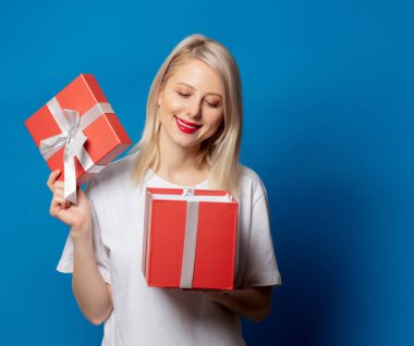 Mavi arka planda hediye kutusu olan beyaz tişörtlü kız.