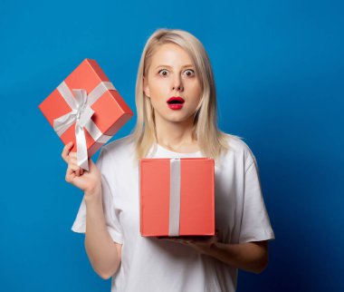 Mavi arka planda hediye kutusu olan beyaz tişörtlü kız.