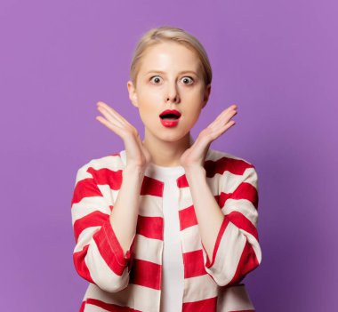 Mor arka planda çizgili ceketli, şaşırmış bir sarışın.