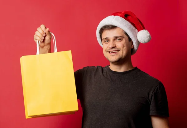 Man Christmas Hat Black Shirt Shopping Bags Red Background — Stock Photo, Image