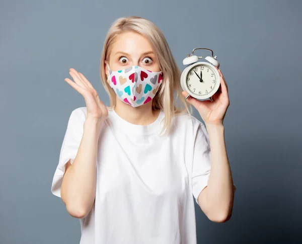 Chica Rubia Mascarilla Con Despertador Sobre Fondo Gris —  Fotos de Stock