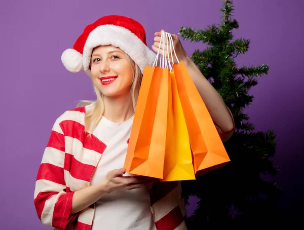 Schöne Blondine Weihnachtsmütze Und Mit Einkaufstaschen Auf Puprle Hintergrund — Stockfoto