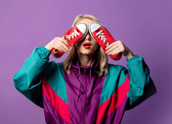 80年代的风衣女士 戴着红色太阳镜 背景是紫色的红色胶鞋 — 图库照片