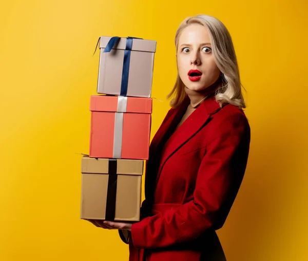 Mulher Loira Casaco Vermelho Com Caixas Presente Fundo Amarelo — Fotografia de Stock