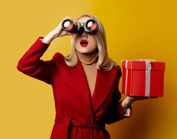 Frau Rotem Mantel Mit Fernglas Und Geschenkbox Auf Gelbem Hintergrund — Stockfoto