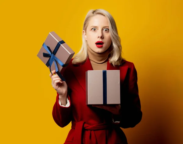 Blonde Überraschte Frau Rotem Mantel Mit Geschenkbox Auf Gelbem Hintergrund — Stockfoto
