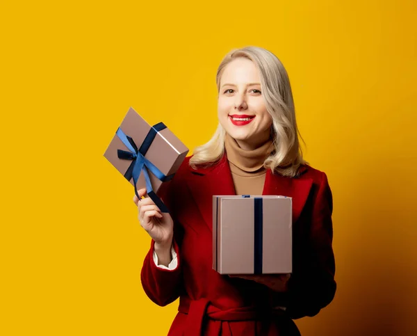 Mulher Sorrindo Loira Casaco Vermelho Com Caixa Presente Fundo Amarelo — Fotografia de Stock