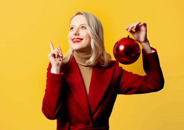 Blonde Woman Red Coat Christmas Bauble Yellow Background — Stock Photo, Image
