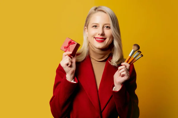 Beautiful Woman Red Coat Brushes Gift Box Yellow Background — Stock Photo, Image