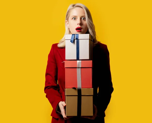Blond Vrouwtje Rode Jas Met Geschenkdoosjes Gele Achtergrond — Stockfoto
