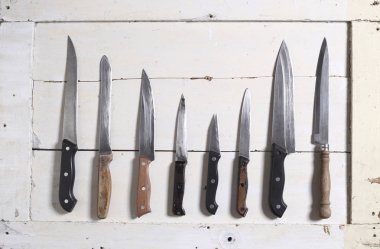 Beyaz ahşap üzerine çeşitli mutfak bıçakları topluluğu