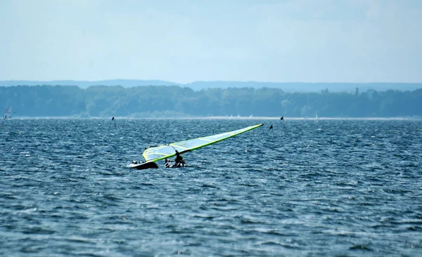 サーファーは夏休みの暖かいポーランドのパック湾でボードで泳いでいます — ストック写真