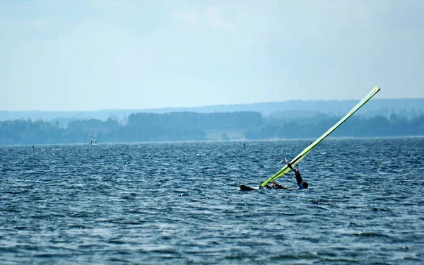 サーファーは夏休みの暖かいポーランドのパック湾でボードで泳いでいます — ストック写真