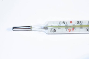 Eski bir cıva termometresi pürüzsüz bir zeminde yakın plan ateşini gösteriyor.