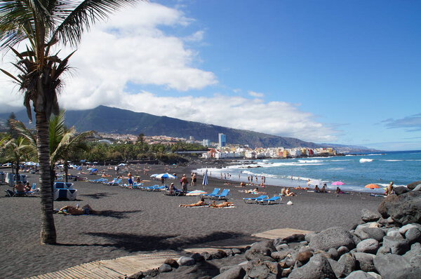 beautiful picturesque Playa Jardin beach on the Spanish Canary Island Tenerife with black volcanic sand blue ocean water and green palm trees