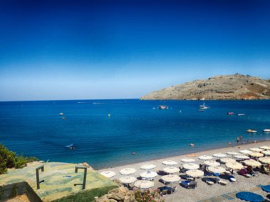 Yunan adası Rodos 'ta sıcak bir yaz günü mavi suyu ve şeridi olan güzel bir sahil.