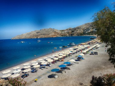 Yunan adası Rodos 'ta sıcak bir yaz günü mavi suyu ve şeridi olan güzel bir sahil.