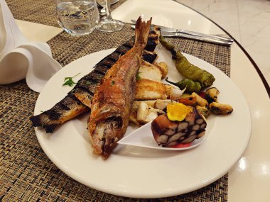 sağlıklı taze ızgara deniz balığı ve yeşil biberler beyaz tabakta