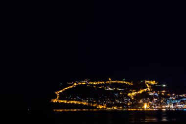 Tepesinde ışıklar olan Türk şehri Alanya 'nın güzel gece manzarası